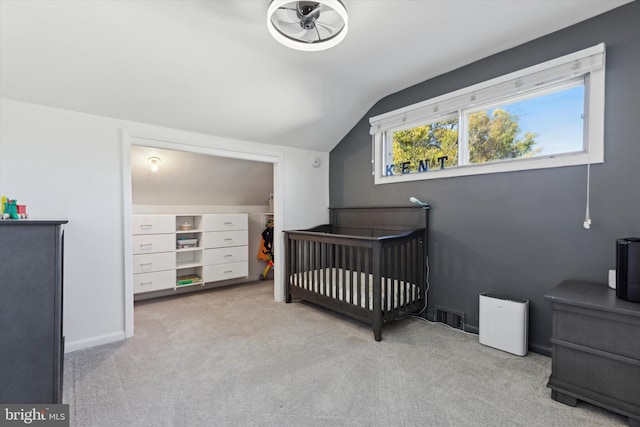 carpeted bedroom with visible vents, a crib, baseboards, and lofted ceiling