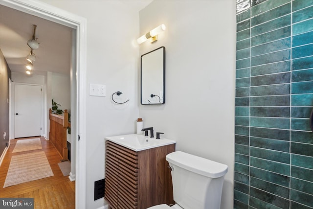 bathroom featuring vanity, track lighting, and toilet