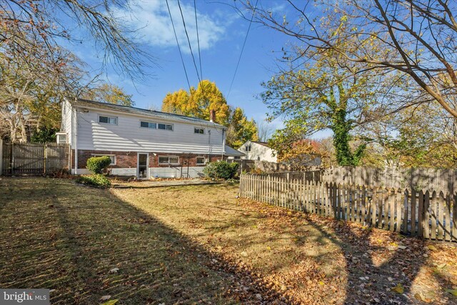 back of property featuring brick siding, a lawn, and a fenced backyard