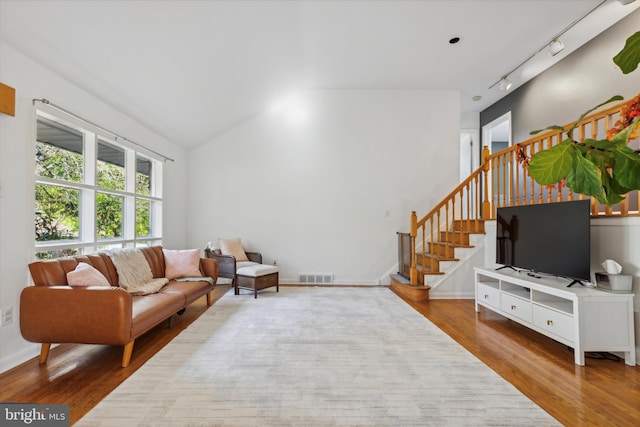living area featuring wood finished floors, visible vents, stairs, vaulted ceiling, and track lighting