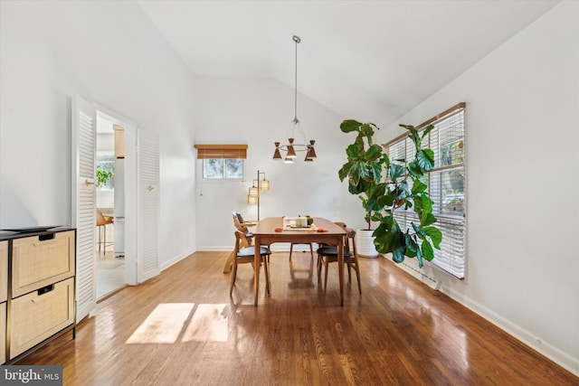 dining space with a chandelier, baseboards, light wood-style floors, and vaulted ceiling