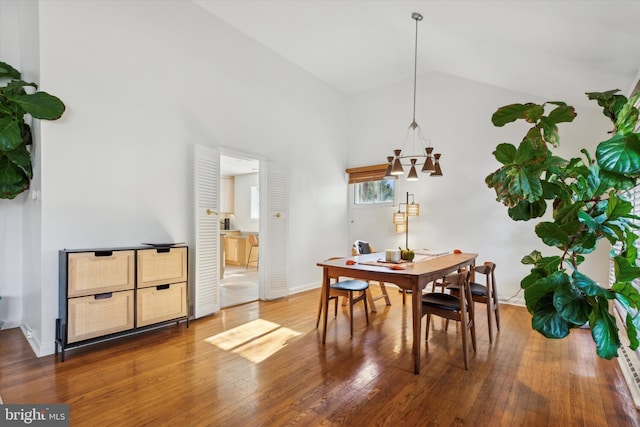 dining room with baseboards, lofted ceiling, and hardwood / wood-style floors