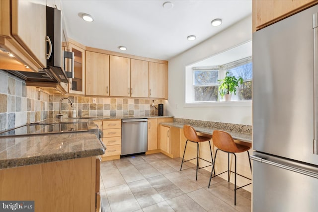 kitchen with decorative backsplash, light brown cabinetry, light stone counters, stainless steel appliances, and glass insert cabinets