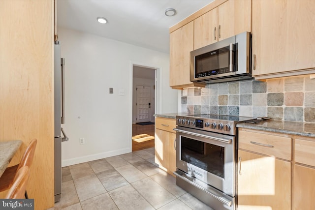 kitchen featuring light brown cabinets, appliances with stainless steel finishes, light tile patterned floors, decorative backsplash, and baseboards