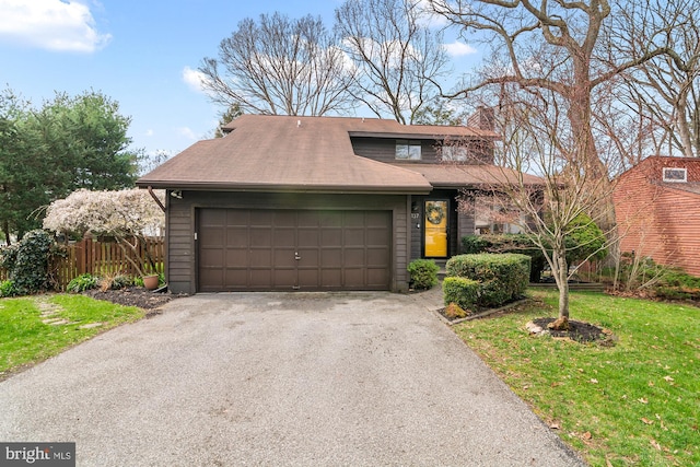 view of front of house featuring a front yard, an attached garage, and fence