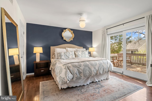 bedroom with hardwood / wood-style floors, baseboards, access to exterior, and an accent wall