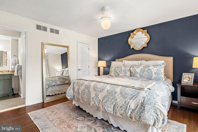 bedroom featuring baseboards, wood finished floors, and an accent wall
