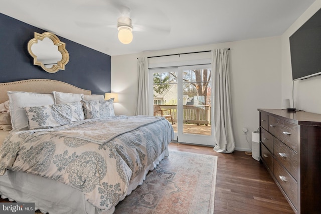 bedroom featuring dark wood-type flooring, baseboards, an accent wall, access to exterior, and ceiling fan