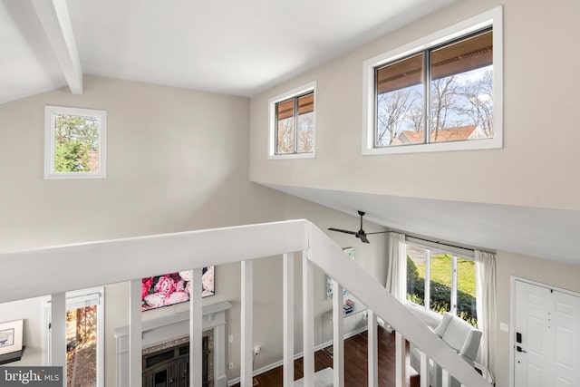 interior space featuring ceiling fan, wood finished floors, beam ceiling, and a fireplace