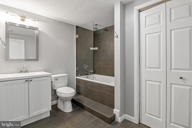 bathroom featuring baseboards, toilet, tiled shower / bath combo, and vanity