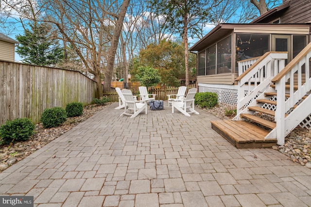 view of patio / terrace featuring a fenced backyard, an outdoor fire pit, and a sunroom