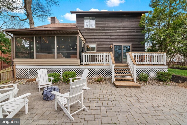 rear view of property with a deck, a sunroom, and a patio area