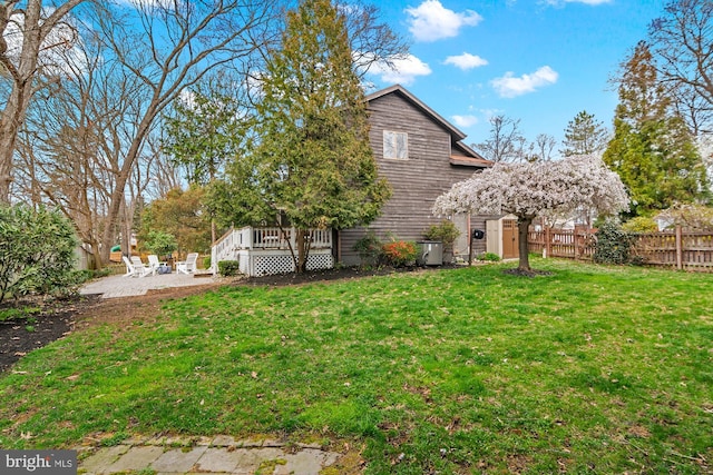 view of yard featuring a wooden deck, fence, and a patio