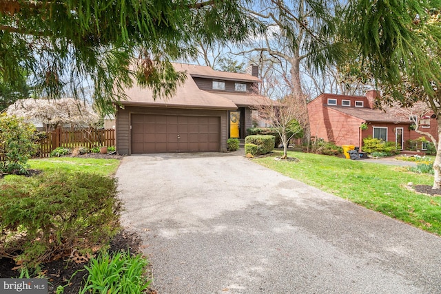 mid-century modern home with fence, aphalt driveway, a front yard, a garage, and a chimney