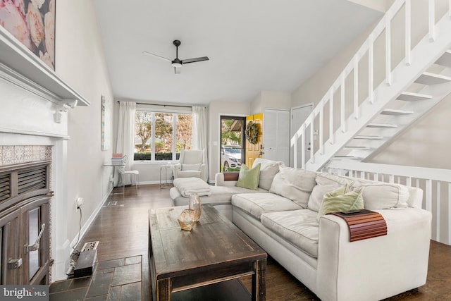 living area with vaulted ceiling, a ceiling fan, a glass covered fireplace, baseboards, and dark wood-type flooring