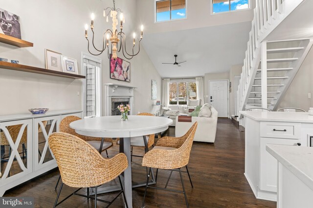dining space with plenty of natural light, ceiling fan with notable chandelier, a fireplace, and stairs