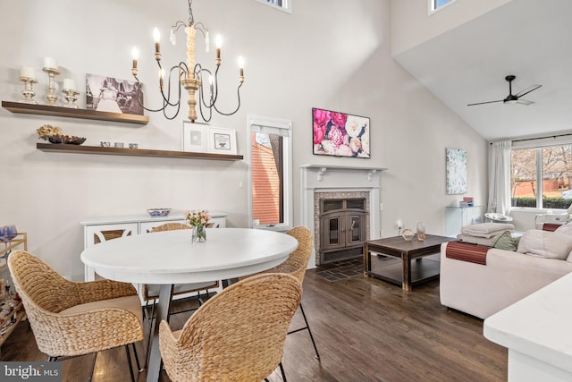 dining space featuring ceiling fan with notable chandelier, high vaulted ceiling, and dark wood-style floors