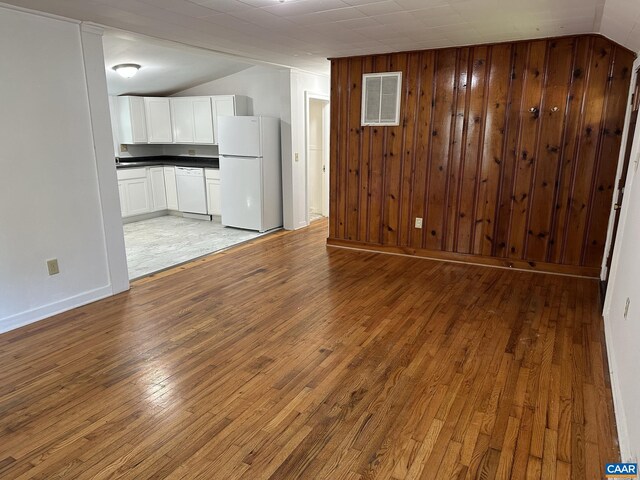 1616 Mulberry Ave, Charlottesville, VA 22903 - unfurnished living room featuring visible vents, wooden walls, light wood-style flooring, and vaulted ceiling