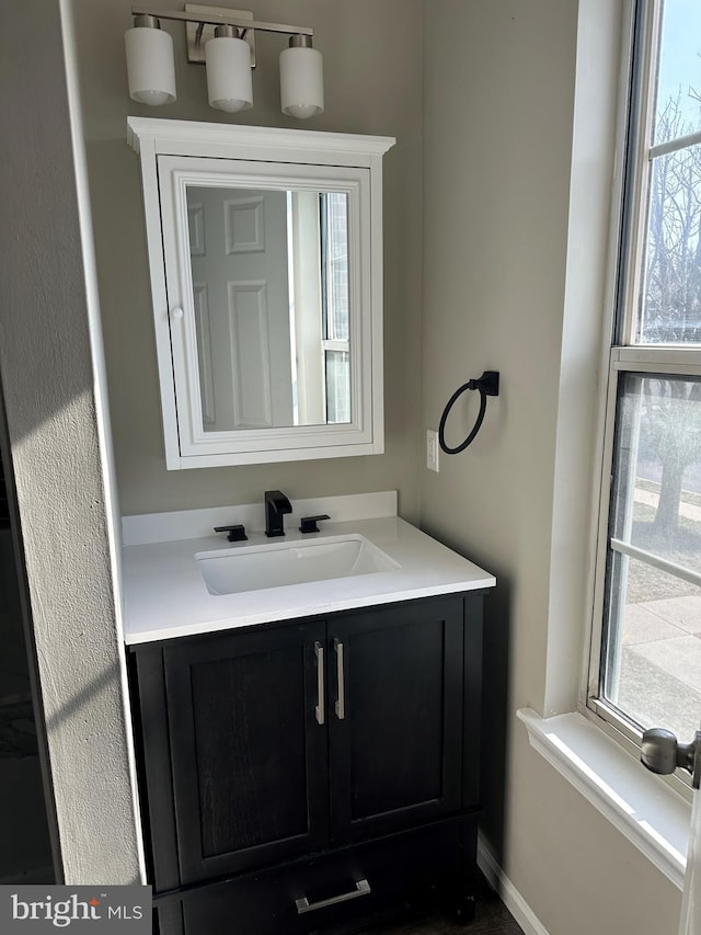 bathroom featuring vanity, baseboards, and a wealth of natural light