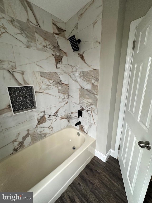 bathroom featuring shower / bathing tub combination, baseboards, and wood finished floors