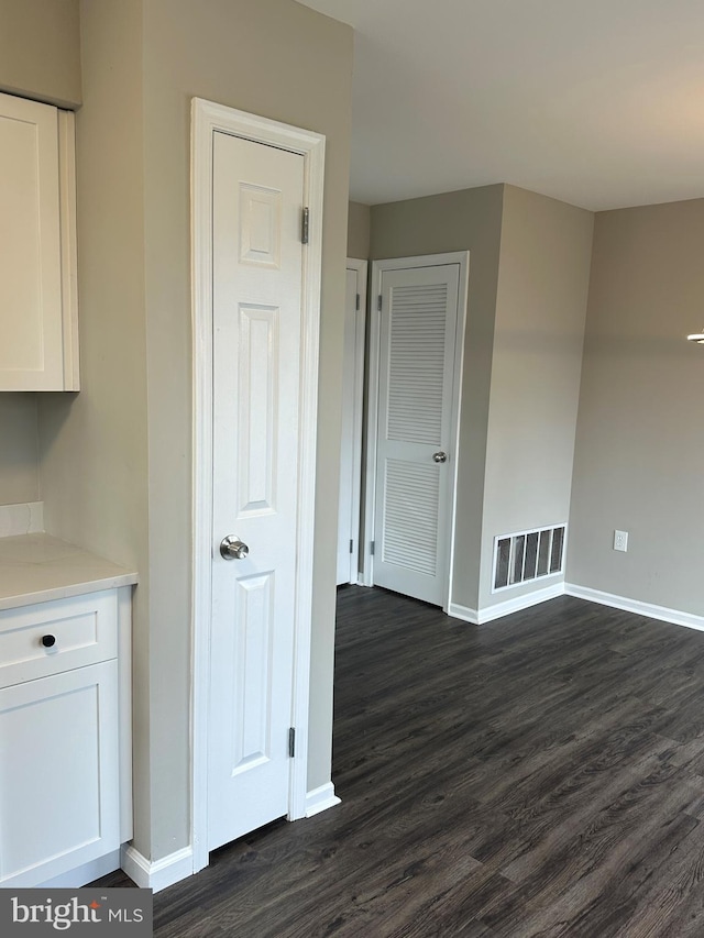 interior space featuring visible vents, dark wood-type flooring, white cabinets, light countertops, and baseboards