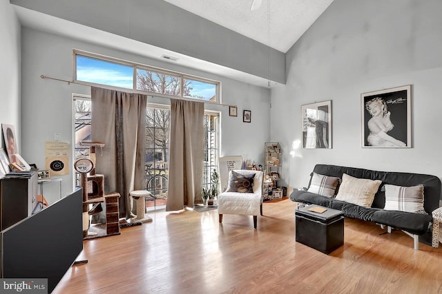 living room featuring visible vents, high vaulted ceiling, and wood finished floors