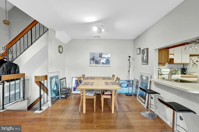 dining area featuring stairs, baseboards, visible vents, and light wood finished floors