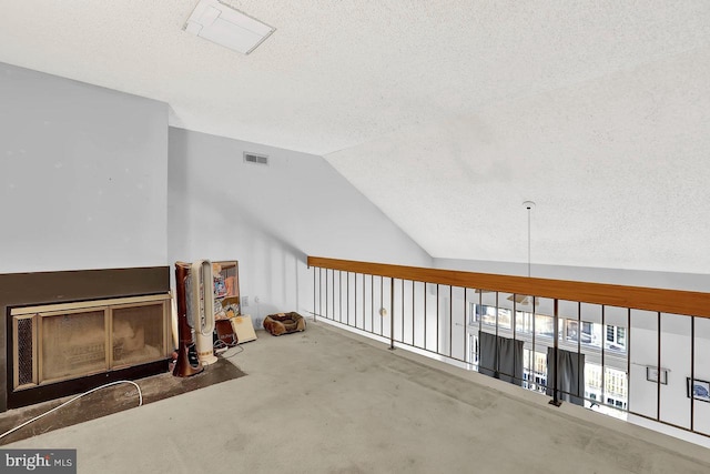 additional living space featuring visible vents, a textured ceiling, carpet, and lofted ceiling