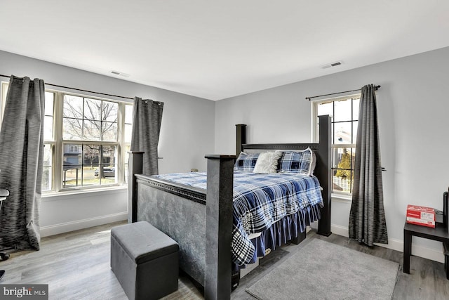 bedroom with multiple windows, baseboards, and wood finished floors