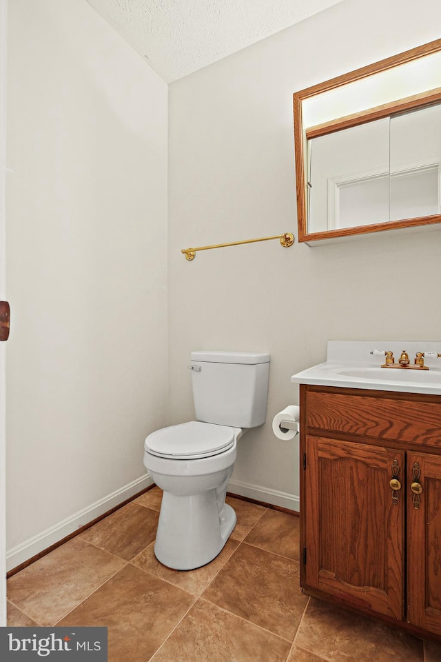 bathroom featuring toilet, vanity, baseboards, and a textured ceiling