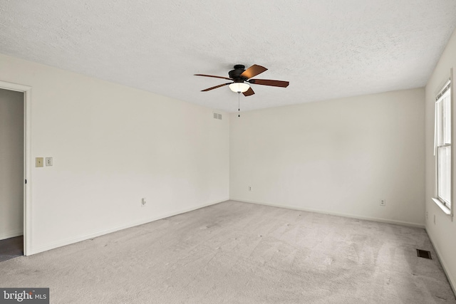 spare room featuring carpet floors, a textured ceiling, visible vents, and a ceiling fan