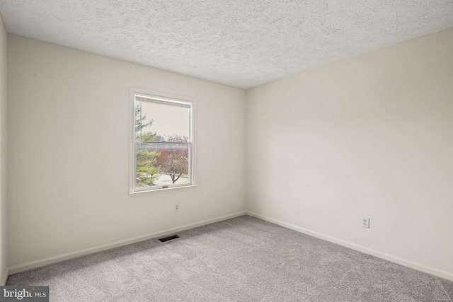 spare room featuring baseboards, visible vents, carpet floors, and a textured ceiling