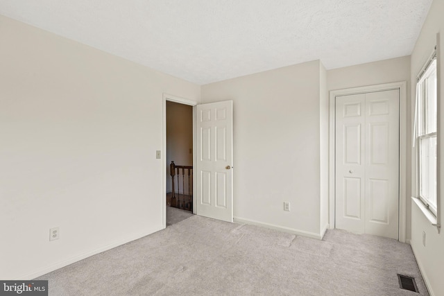 unfurnished bedroom featuring carpet flooring, visible vents, baseboards, and a textured ceiling