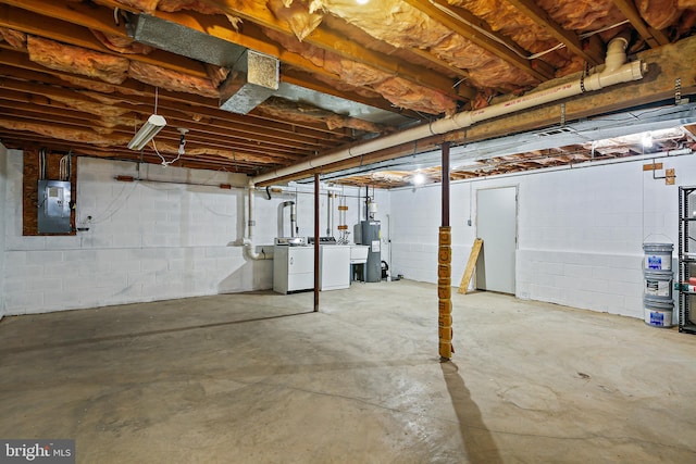 unfinished basement featuring independent washer and dryer, electric panel, and electric water heater