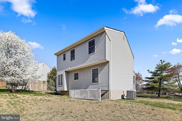 rear view of house with central air condition unit and a yard
