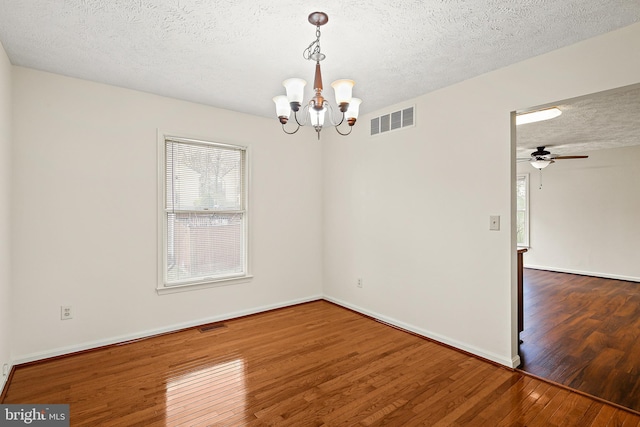 unfurnished room with hardwood / wood-style flooring, baseboards, a textured ceiling, and visible vents