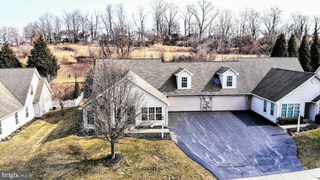 new england style home with aphalt driveway, an attached garage, a front lawn, and roof with shingles