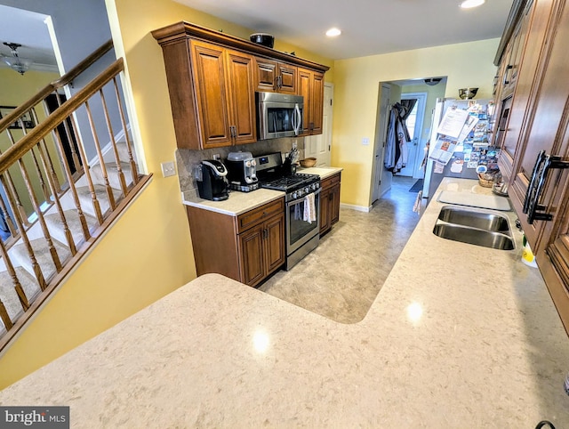 kitchen with baseboards, recessed lighting, a sink, light countertops, and appliances with stainless steel finishes