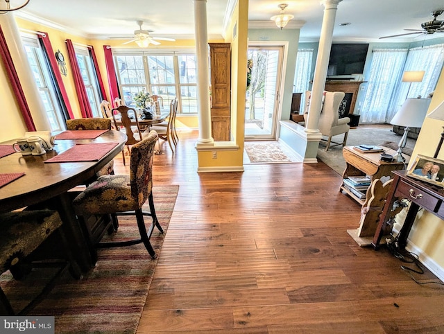 dining room featuring ornate columns, dark wood finished floors, a fireplace, ceiling fan, and crown molding