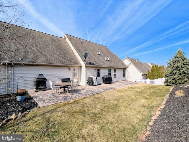 rear view of house featuring fence, a lawn, a shingled roof, and a patio area