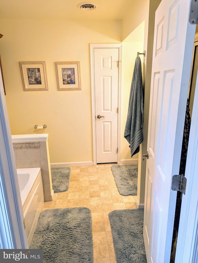 full bath with tile patterned flooring, a garden tub, baseboards, and visible vents