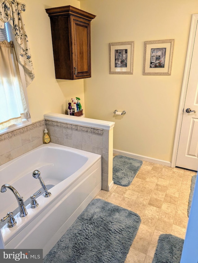 bathroom featuring tile patterned floors, baseboards, and a bath