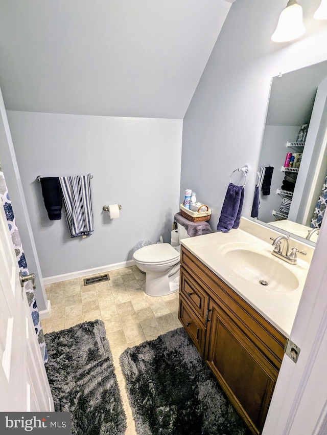 bathroom with vanity, baseboards, visible vents, lofted ceiling, and toilet