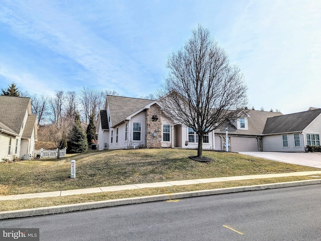 view of front of house featuring a front yard, fence, roof with shingles, an attached garage, and concrete driveway