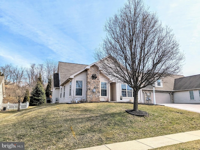 single story home with a shingled roof, fence, concrete driveway, a front yard, and stone siding