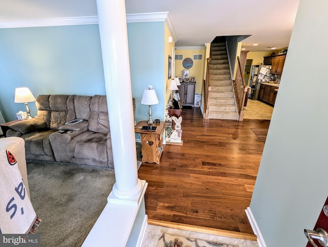 living room featuring dark wood-type flooring, ornamental molding, decorative columns, baseboards, and stairs