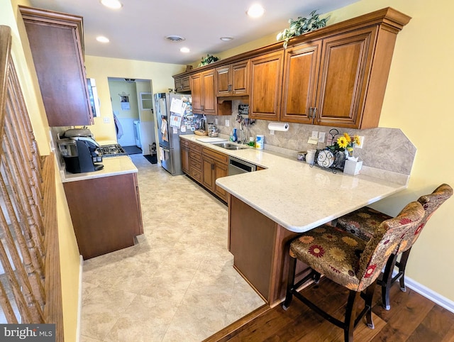 kitchen with visible vents, light countertops, decorative backsplash, a peninsula, and freestanding refrigerator