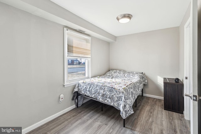 bedroom with visible vents, wood finished floors, and baseboards