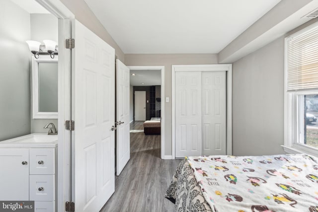 bedroom featuring a sink, a closet, visible vents, and wood finished floors