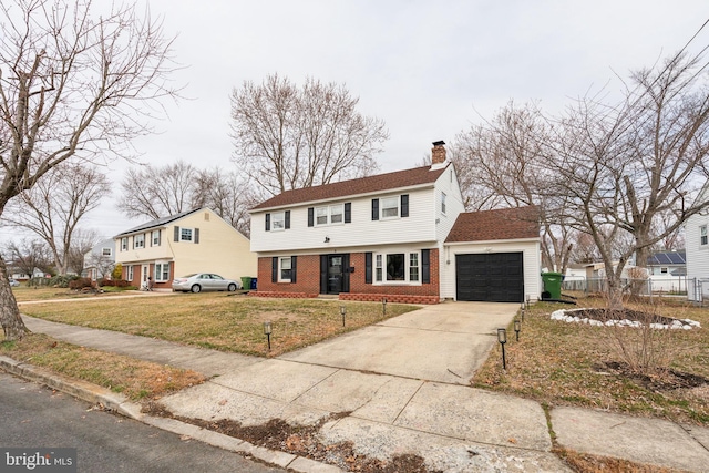 colonial-style house with a front yard, fence, a chimney, concrete driveway, and brick siding